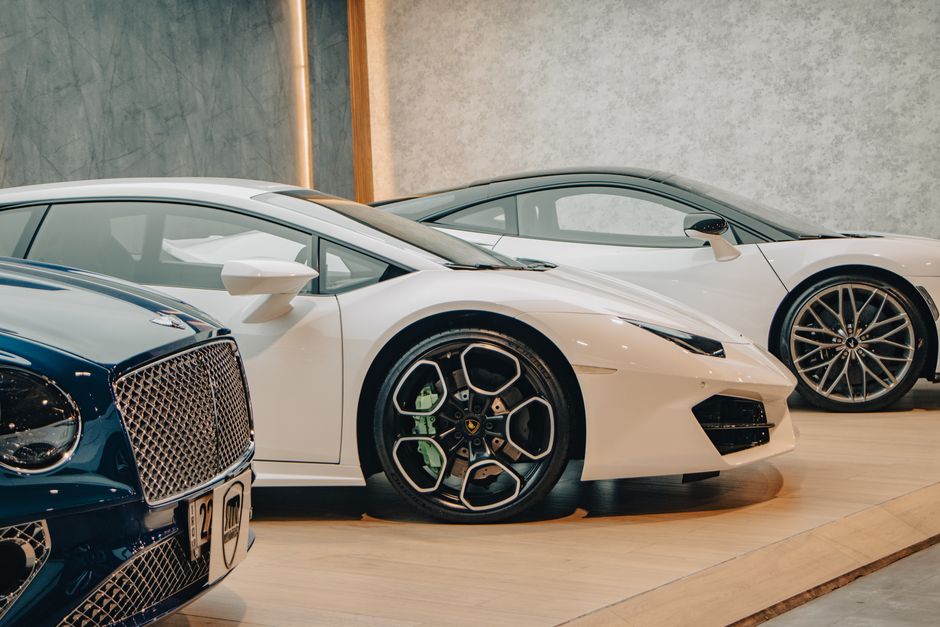 A lineup of sleek luxury sports cars on display in an upscale showroom setting.