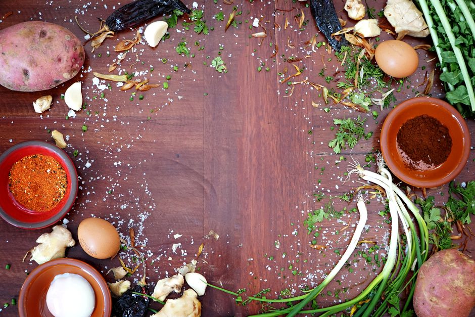 A vibrant collection of fresh ingredients and spices on a wooden table with ample copyspace.